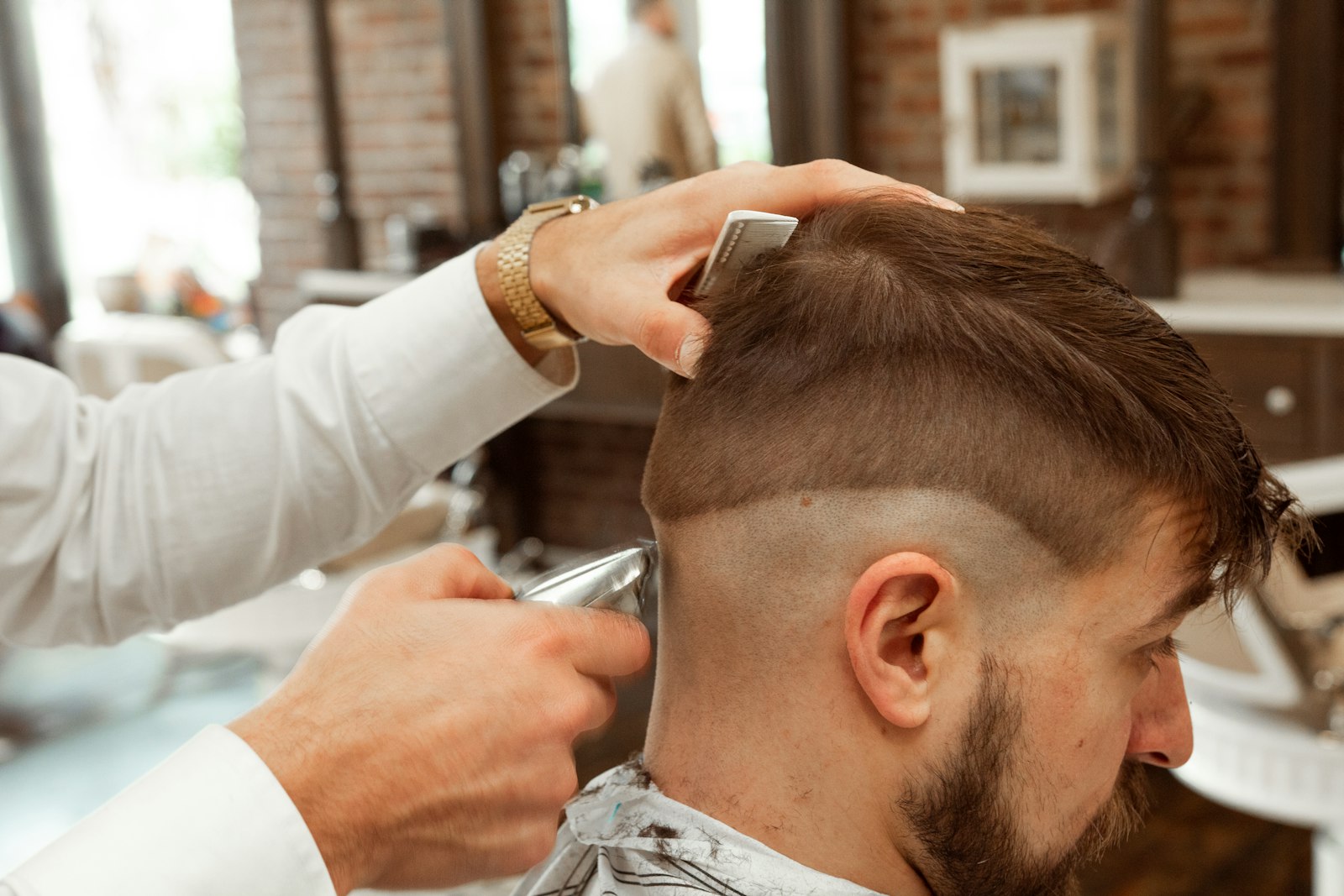 A barber finishing a fade at the middle chair